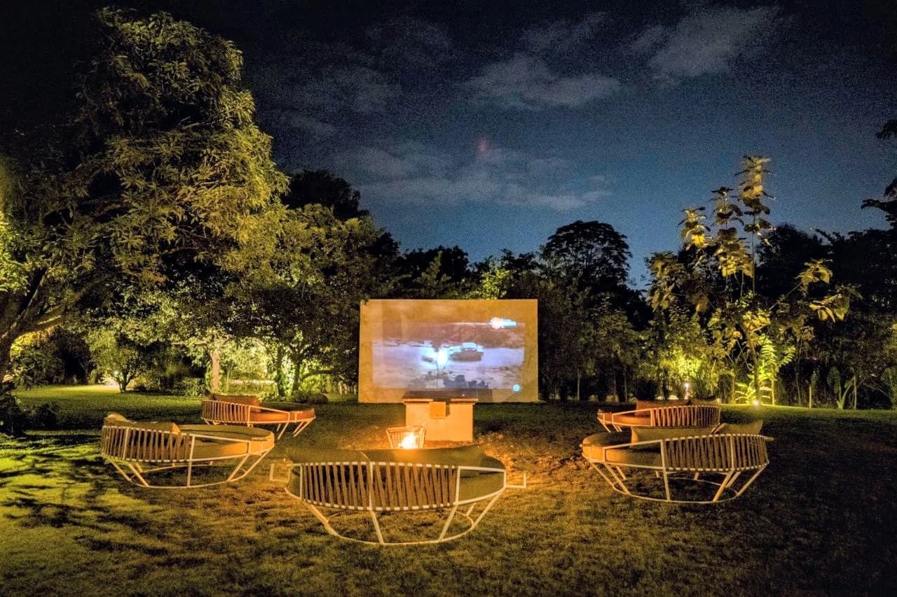 The open-air theatre at night — loungers around a fire pit before the screen
