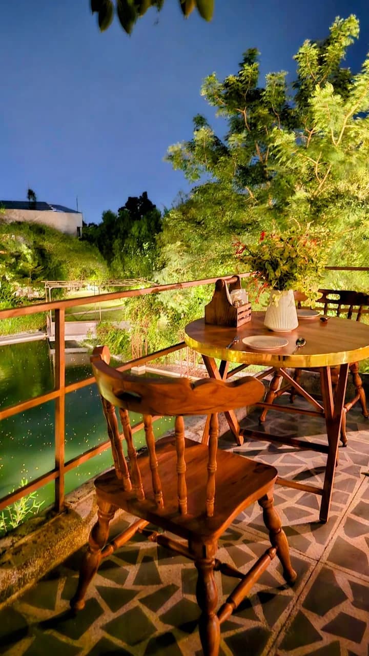 A lantern-lit dinner table set beside the lily pond at dusk